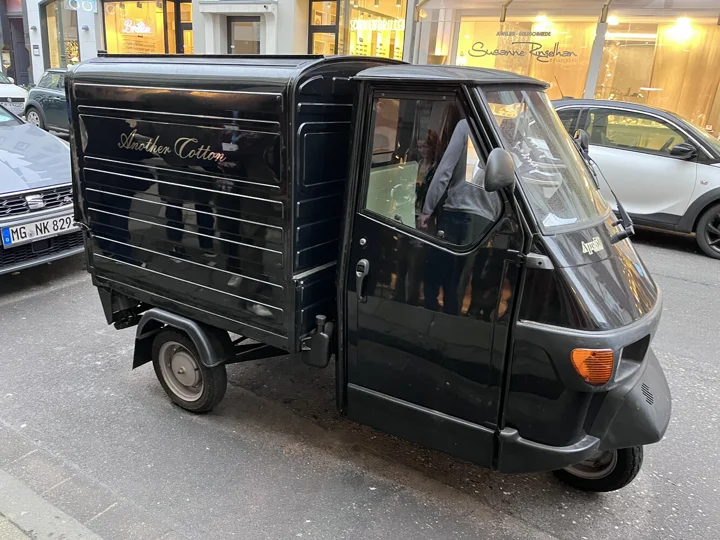 Před obchodem stojí autíčko fungující jako pojízdná kavárna, která doprovází místní běžce na závody.